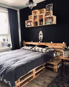 a bed made out of wooden pallets in a room with black walls and wood flooring