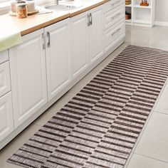 a kitchen with white cabinets and brown rugs on the floor in front of sink