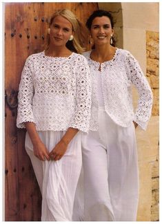 two women standing next to each other in front of a wooden wall wearing white clothing