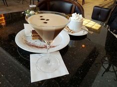 a table with two desserts on it and a drink in the glass next to it