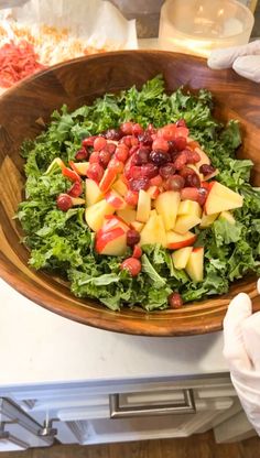 a wooden bowl filled with fruit and vegetables on top of a table next to other food items