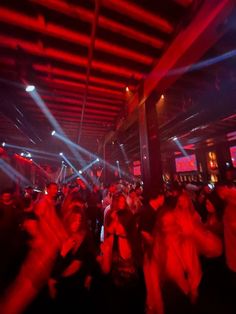 a group of people dancing in a room with red and blue lights on the ceiling