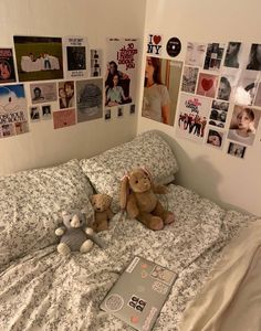 a teddy bear sitting on top of a bed in a room with many pictures hanging on the wall