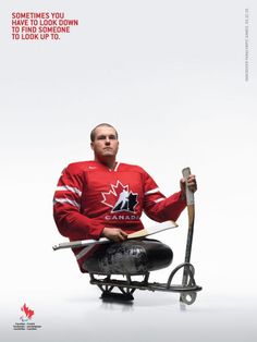 a man sitting on top of a chair holding a hockey stick and wearing a red jersey