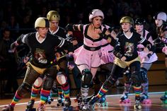 several roller skaters in colorful costumes are skating on the court with spectators behind them