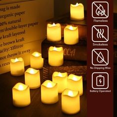 many lit candles sitting on top of a table next to some books and a sign