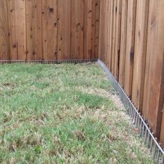 a fence that is next to a grassy area in the yard with grass growing on it