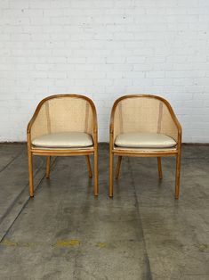 two chairs sitting next to each other in front of a white brick wall and cement floor