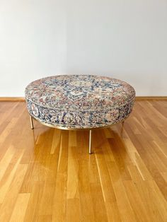 a round ottoman sitting on top of a hard wood floor