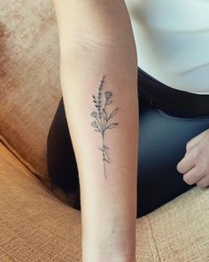 a woman's arm with a small flower tattoo on the left side of her right arm