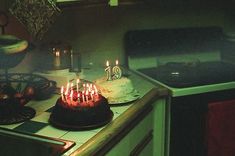 a birthday cake with lit candles sitting on top of a counter next to a stove