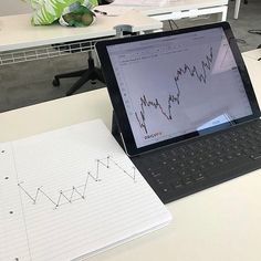 an open laptop computer sitting on top of a desk next to a pen and paper