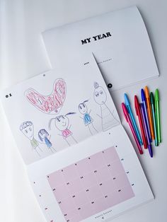 a calendar with colored markers next to it on a white surface, and an image of a cartoon character