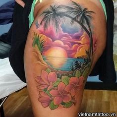 a woman's thigh with flowers and palm trees on the beach in front of her