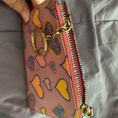 a person is holding a pink purse with gold rings on the front and bottom zipper