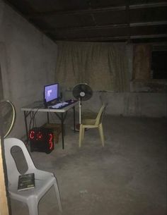 a room with a table, chair and laptop on it