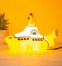 a yellow submarine lamp sitting on top of a table next to a potted plant