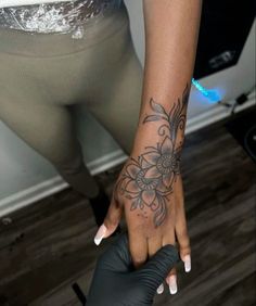 a woman's hand with a flower tattoo on her left arm and the bottom half of her leg