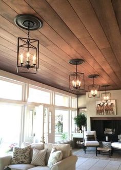 a living room filled with lots of furniture and lights hanging from the ceiling next to a fire place