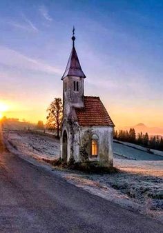 an old church sits on the side of a rural road at sunset in wintertime