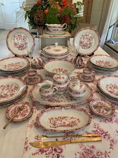 a table topped with lots of plates covered in red and white designs next to a vase filled with flowers