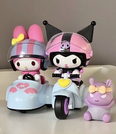 two hello kitty dolls are riding on a toy motorcycle and an animal is standing next to them