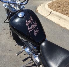 a black motorcycle parked on the street next to a curb with graffiti written on it