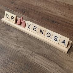 scrabble letters spelling the word dravenosa on a wooden surface