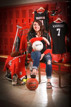 a woman sitting on a bench with a basketball and other sports memorabilia in the background