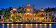 a large house with lots of windows and lights on the front is lit up at night