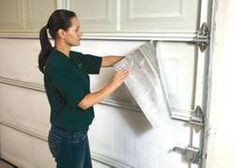 a woman is holding up a piece of duct taped to the side of a garage door