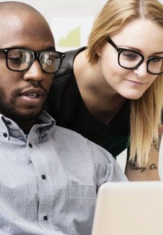 a man and woman looking at a laptop computer screen while they look at the screen