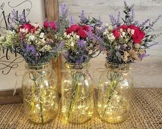 three vases filled with flowers sitting on top of a burlick covered table