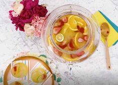 a glass jar filled with sliced fruit on top of a table next to plates and flowers