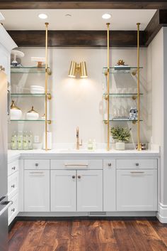 a kitchen with white cabinets and gold trim on the shelves, along with brass fixtures