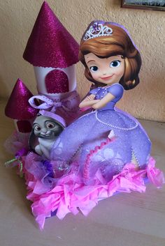 there is a princess figurine sitting on top of a purple dress with a castle in the background