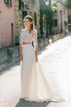 a woman in a white dress is standing on the street with her hands behind her back