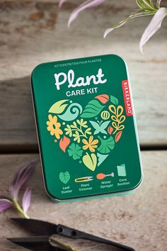 a plant care kit sitting on top of a wooden table next to scissors and flowers