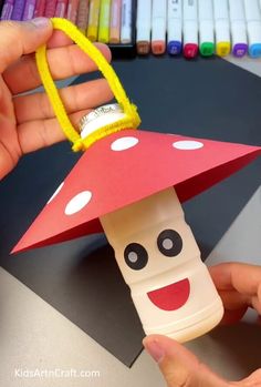 a hand holding a paper toy with a mushroom on it