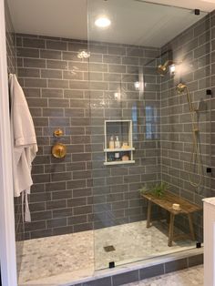 a walk in shower sitting next to a wooden bench under a light on the wall