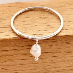 🌷These gorgeous little Pearl charm rings will also make a beautiful fidget ring. The tiny natural salt water Pearl moves around the band and looks extremely elegant. These rings are handmade and made to order in the size of your choice. Please choose the ring size of your choice from the drop down ring chart. 🌷Ring dimensions: 925 sterling silver 1.2mm gauge. Pearl charm: 6 mm 🌷Your beautiful ring will arrive gift wrapped and in a lovely gift pouch and will be sent first class with tracking. Adjustable Minimalist Sterling Silver Pearl Ring, Dainty Stackable Sterling Silver Pearl Ring, Minimalist Stackable Sterling Silver Pearl Ring, Minimalist Pearl Charm Promise Ring, Delicate Sterling Silver Pearl Promise Ring, Minimalist Promise Ring With Pearl Charm, Dainty Sterling Silver Pearl Ring For Everyday, Dainty Pearl Charm Ring For Gift, Sterling Silver Pearl Drop Ring