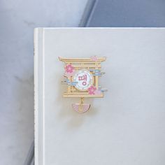 a brooch that is sitting on top of a white book with pink and blue flowers