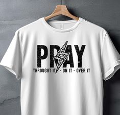 Embrace your faith with our Pray Through It On It Over It T-Shirt. This inspirational shirt is perfect for those seeking encouragement and motivation. The bold design serves as a daily reminder of your spiritual journey. Great for casual wear or a thoughtful gift for loved ones. Pray Through It, Message Positif, Christian Motivation, Faith Shirt, Inspirational Shirt, Positive Messages, Bold Design, Over It, Spiritual Journey