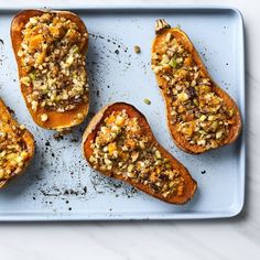 four stuffed sweet potatoes on a baking sheet with nuts and crumbled toppings