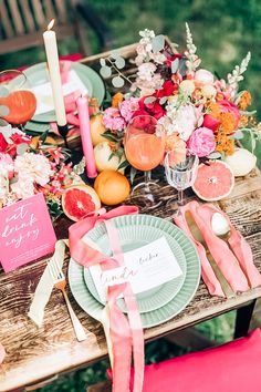 the table is set with plates, napkins and candles for an outdoor wedding reception