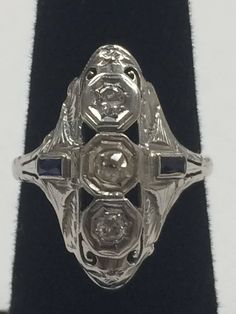 "Vintage 1940's 14K White Gold .50CTW Diamond and Sapphire Ring This beautiful, well made ring will become a family heirloom! 2 round .15ct diamonds set in a row with 2 - .3ct sapphires on side of band. Ring face measures approximately 1\" x 1/2\" Size 6.25 3.1 grams total weight. In excellent vintage condition!" Antique Three-stone Diamond White Rings, Antique Three Stone Diamond White Rings, Antique Three Stone Round Diamond Ring, Antique Oval Three Stone Diamond Ring, Antique Three-stone Diamond Rings, Antique Three Stone Platinum Rings, Antique Platinum Three Stone Rings, Art Deco Three Stone Diamond Ring, Antique Three Stone Round Rings