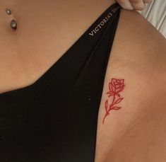 a woman with a red rose tattoo on her left shoulder and right arm behind her back