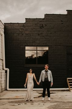 a man and woman holding hands in front of a building