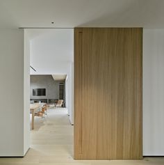 an open door leading to a dining room and living room with white walls, wood flooring and wooden furniture