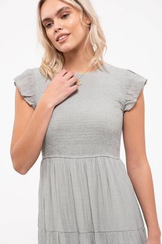 This solid midi-length dress features a smocked body, tiered skirt, and round neckline with a back button and ruffle cap sleeves. Both casual and elegant, this will be a summer staple. Midi Dress With Ruffle Sleeves For Brunch, Casual Dress With Smocked Back And Ruffle Sleeve, Spring Midi Dress With Flutter Sleeves In Solid Color, Summer Midi Dress With Smocked Bodice And Ruffle Sleeves, Casual Midi Dress With Smocked Bodice And Flutter Sleeves, Casual Midi Dress With Smocked Back And Ruffle Sleeve, Casual Cap Sleeve Dress With Ruffles, Spring Midi Dress With Smocked Bodice And Ruffle Sleeves, Casual Midi Dress With Flutter Sleeve And Ruffle Hem